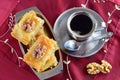 Traditional Greek baklava made with filo dough, sugar syrup and wallnuts on a metal tray with metal coffee cup on a