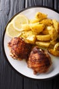 Traditional Greek Lemon Garlic Roasted Potatoes Patates fournou with grilled chicken thighs on a plate close-up. Vertical top