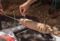 Traditional Greek meat roll Kokoretsi sprinkled with salt on a spindle