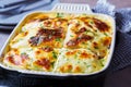 Traditional Greek moussaka - potato and meat casserole with cheese in black oven dish, dark background. Greek food concept