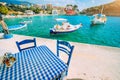 Traditional Greek restaurant with blue and white table and chairs at the sea coast of Assos village. Azure water