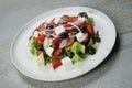 Traditional Greek salad on marble plate, stone background