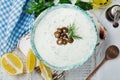 Traditional Greek sauce Tzatziki. Yogurt, cucumber, dill, garlic and salt oil in a ceramic bowl on a light wooden background. Royalty Free Stock Photo