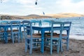 Traditional greek tavern with wooden tables on sandy beach near water waiting for tourists in Tolo, Peloponnese, Greece