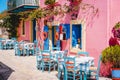 Traditional greek vivid lilac colored tavern on the narrow Mediterranean street on hot summer day Royalty Free Stock Photo