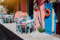 Traditional greek vivid lilac colored tavern on the narrow Mediterranean street on hot summer day