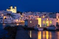 Greek whitewashed houses and church by harbour watersfront after sunset, Naoussa, Paros island, Greece Royalty Free Stock Photo