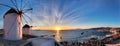 Traditional greek windmills on Mykonos island on sunset with dramatic sky and Little Venice quarter with tourist crowd