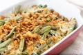 A traditional green bean casserole topped with French Fried Onions and cream of mushroom on white marble Royalty Free Stock Photo