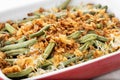 A traditional green bean casserole topped with French Fried Onions and cream of mushroom on white marble Royalty Free Stock Photo