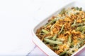 A traditional green bean casserole topped with French Fried Onions and cream of mushroom on white marble. Royalty Free Stock Photo