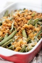 A traditional green bean casserole topped with French Fried Onions and cream of mushroom on white marble Royalty Free Stock Photo