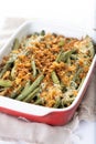 A traditional green bean casserole topped with French Fried Onions and cream of mushroom on white marble. Royalty Free Stock Photo