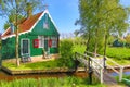 Traditional green dutch house with little wooden bridge against blue sky in the Zaanse Schans village, Netherlands. Famous tourism Royalty Free Stock Photo