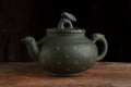 Green traditional chinese Yixin clay teapot with cicada on the cover. On the wooden table and black backround Royalty Free Stock Photo
