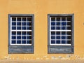 Traditional guillotine windows in historic colonial house. Two old style blue wooden windows on a bright orange wall. Urbanism and