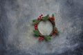 Traditional Handmade Christmas Wreath Green Fir Tree Branches Twigs Holly Berries on Grungy Dark Stone Background. Top View Royalty Free Stock Photo