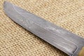 Traditional handmade Finnish knife with the abstract wave pattern of damascus steel over an old sack background. Royalty Free Stock Photo