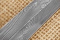Traditional handmade Finnish knife with the abstract wave pattern of damascus steel over an old sack background. Royalty Free Stock Photo