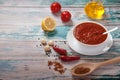 Traditional harissa in a porcelain cup, red hot chili pepper, lemon, oil, garlic and spices in a wooden spoon on a white Royalty Free Stock Photo