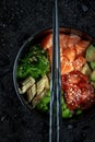 Traditional Hawaiian Poke bowl salad with vegetables and raw salmon fish, top view on black background Royalty Free Stock Photo