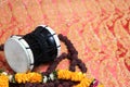 Traditional hindu prayer beads rudraksha and musical instrument of God Shiva Damaru drum on a red saree background