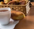 Traditional Homemade Baked Patties or Pies with Jam in a Wicker Basket next to a White Cup of Tea