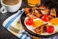 Traditional homemade english american breakfast, fried eggs, toasts, bacon, with coffee mug and orange juice dark background, top Royalty Free Stock Photo