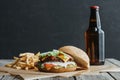 traditional homemade hamburger, french fries and bottle of beer on baking paper Royalty Free Stock Photo