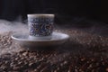 traditional hot coffee cup with beans and smoke steam over a black background. Royalty Free Stock Photo