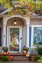 Traditional house with porch decorated for fall with partly eaten pumpkins and a squirrel eating another one - distorted