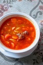 Traditional Hungarian hot goulash soup with bread, background is traditional grey embroidery lace table.