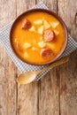 Traditional Hungarian thick potato soup with sausages close-up in a plate. vertical top view
