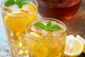 Traditional iced tea with lemon, mint and ice in tall glasses. Two glasses with cool summer drink on old rusty background