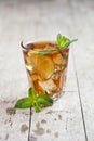 Traditional iced tea with lemon, mint leaves and ice in glass on rustic wooden table