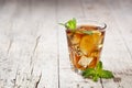Traditional iced tea with lemon, mint leaves and ice in glass on rustic wooden table background
