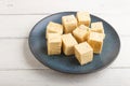 Traditional indian candy soan papdi in a blue ceramic plate with almond and pistache on a white wooden background. side view Royalty Free Stock Photo