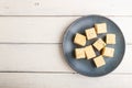 Traditional indian candy soan papdi in a blue ceramic plate with almond and pistache on a white wooden background. top view Royalty Free Stock Photo