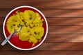 Traditional Indian dessert kesari with raisins on red plate on wooden table. top view