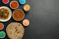 Traditional Indian food and color powders on black table, flat lay with space for text. Holi festival celebration Royalty Free Stock Photo