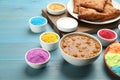 Traditional Indian food and color powders on light blue wooden table. Holi festival celebration Royalty Free Stock Photo