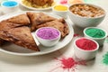 Traditional Indian food and color powders on white wooden table, closeup. Holi festival celebration Royalty Free Stock Photo