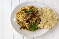 Traditional Indian mutton Biryani served with raita and crispy pappadam on white background. Selective focus. Authentic cuisine