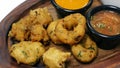 traditional indian snack food, crispy deep fried vada and chutneys close up in a serving plate
