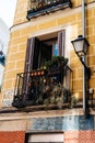 Traditional iron balcony with pots hanging from the railing in Lavapies neighborhood in Madrid