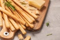 Traditional italian breadsticks grissini with rosemary, parmesan cheese, olive oil, garlic and salt on a gray background