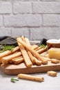 Traditional italian breadsticks grissini with rosemary, parmesan cheese, olive oil, garlic and salt on a gray background