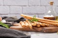 Traditional italian breadsticks grissini with rosemary, parmesan cheese, olive oil, garlic and salt on a gray background