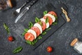 Traditional Italian Caprese Salad - sliced tomatoes, mozzarella cheese and basil on stone background, top view Royalty Free Stock Photo