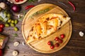 Traditional italian closed pizza Calzone with basil leaves on wooden background